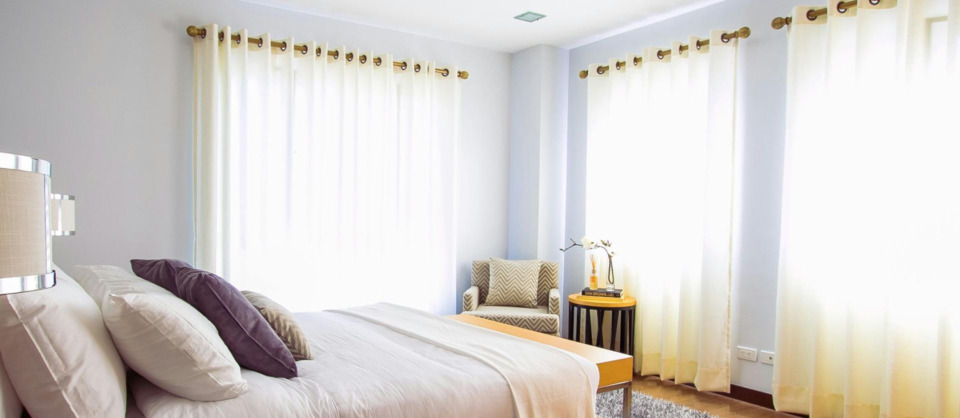 Bright modern bedroom with sunlight, cozy decor, and soft furnishings.